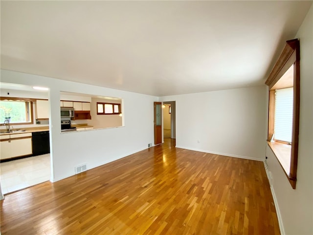 unfurnished living room featuring sink and light hardwood / wood-style floors