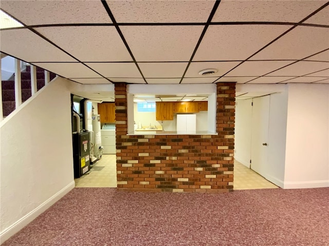 basement with a paneled ceiling, heating unit, and gas water heater