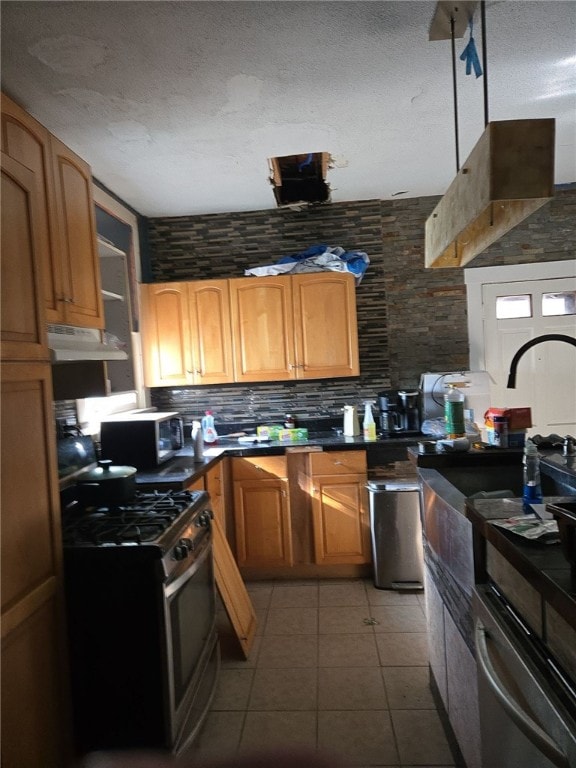 kitchen featuring gas stove, light tile patterned floors, a textured ceiling, and tasteful backsplash