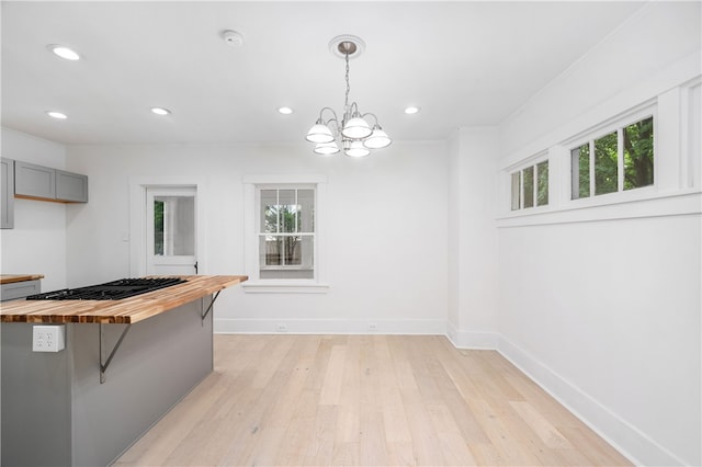 kitchen with wood counters, light hardwood / wood-style floors, a breakfast bar area, and decorative light fixtures