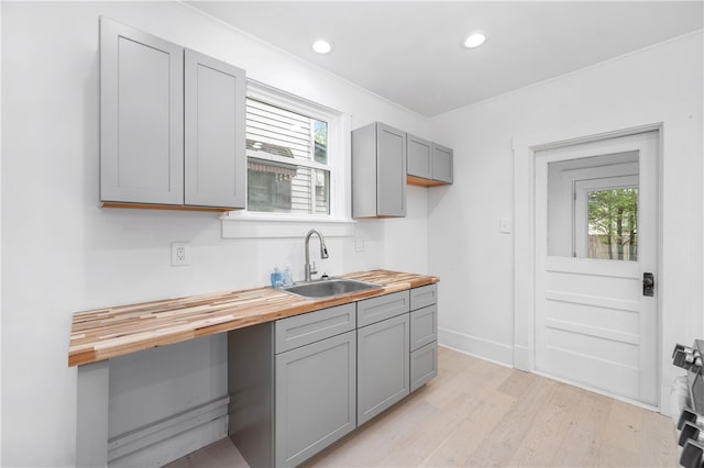 kitchen featuring light hardwood / wood-style floors, butcher block counters, sink, and a wealth of natural light