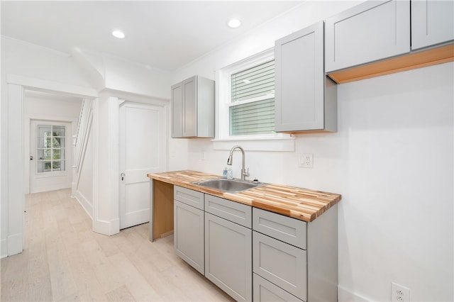 kitchen with butcher block counters, a wealth of natural light, sink, and light hardwood / wood-style flooring