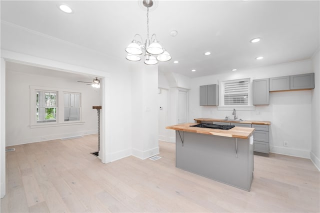 kitchen featuring ceiling fan with notable chandelier, light wood-type flooring, butcher block countertops, and gray cabinets