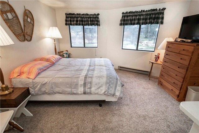 carpeted bedroom featuring baseboard heating and multiple windows