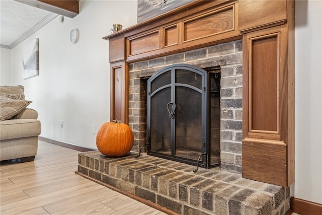 room details with crown molding, hardwood / wood-style floors, beamed ceiling, and a brick fireplace