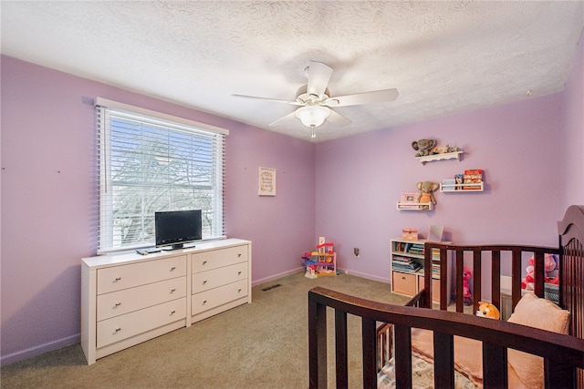 bedroom with a textured ceiling, ceiling fan, and light carpet