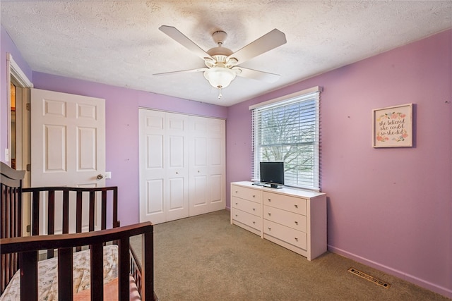 bedroom featuring a textured ceiling, ceiling fan, light carpet, and a closet