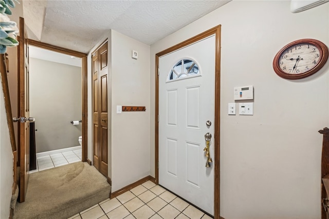 tiled entryway with an AC wall unit and a textured ceiling