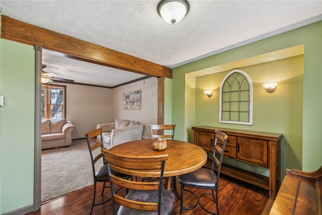 dining room featuring beam ceiling, a textured ceiling, dark hardwood / wood-style floors, and ceiling fan