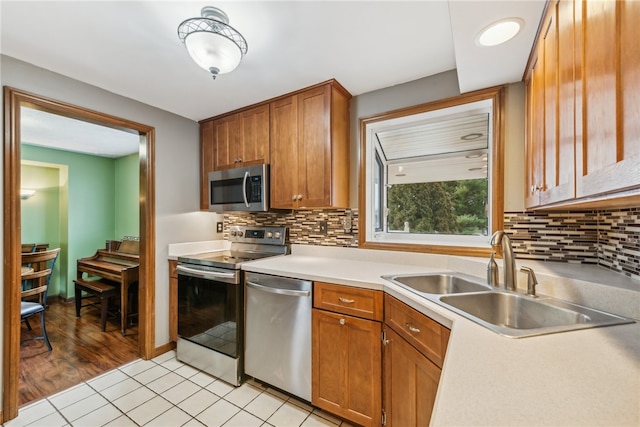 kitchen with appliances with stainless steel finishes, light hardwood / wood-style floors, tasteful backsplash, and sink