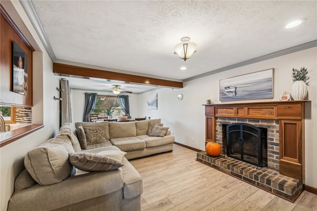 living room with a textured ceiling, light hardwood / wood-style floors, ceiling fan, and ornamental molding