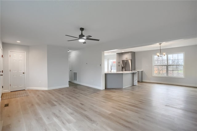 unfurnished living room featuring light hardwood / wood-style floors and ceiling fan with notable chandelier