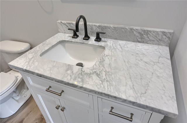 bathroom featuring toilet, vanity, and hardwood / wood-style flooring