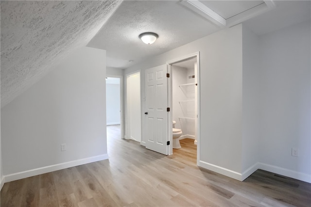 bonus room featuring a textured ceiling and light wood-type flooring