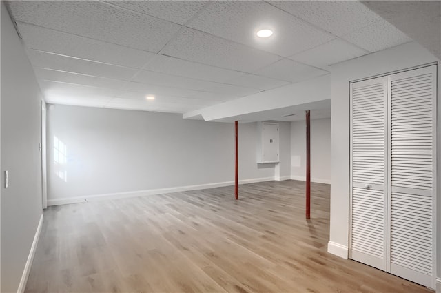 basement with light hardwood / wood-style flooring and a drop ceiling