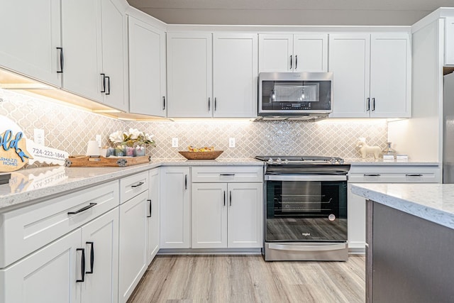 kitchen with light stone countertops, white cabinetry, stainless steel appliances, and light wood-type flooring