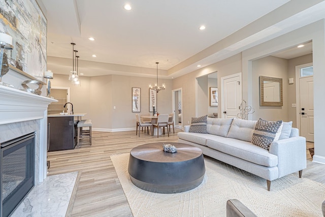 living room with a premium fireplace, light hardwood / wood-style floors, and a notable chandelier