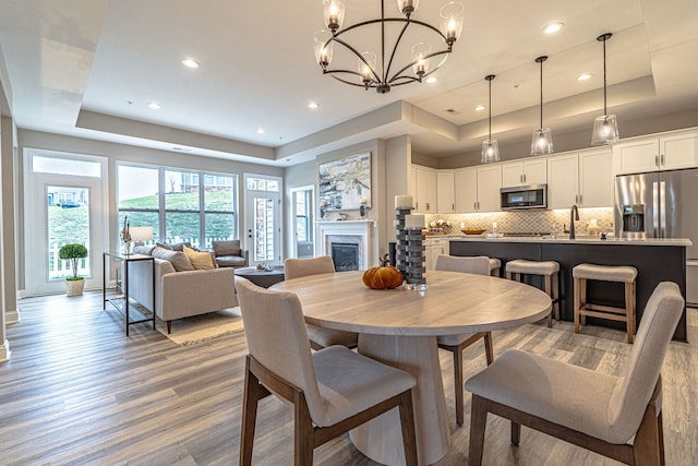 dining room with a raised ceiling, an inviting chandelier, and hardwood / wood-style flooring