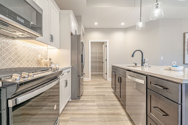 kitchen featuring light stone countertops, stainless steel appliances, sink, light hardwood / wood-style flooring, and white cabinetry