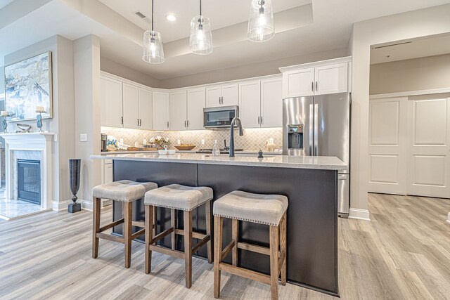 kitchen featuring tasteful backsplash, white cabinetry, appliances with stainless steel finishes, and light hardwood / wood-style flooring