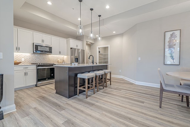 kitchen featuring a center island with sink, white cabinets, and appliances with stainless steel finishes