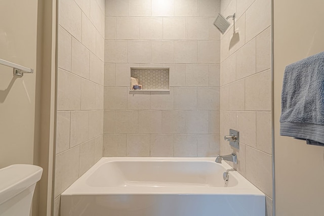 bathroom featuring tiled shower / bath combo and toilet