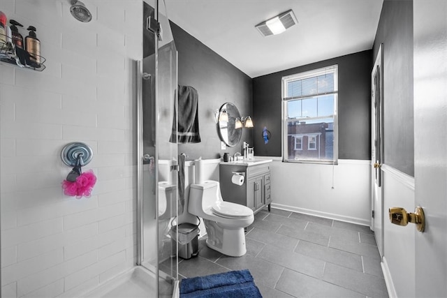 bathroom featuring a tile shower, tile patterned floors, vanity, and toilet