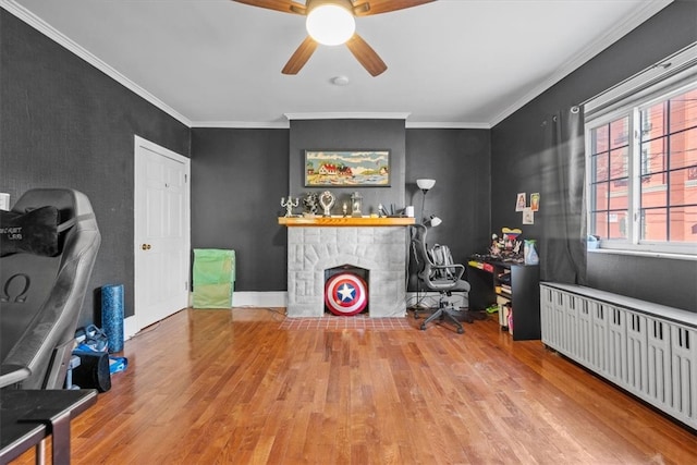 interior space with radiator, ceiling fan, crown molding, hardwood / wood-style floors, and a fireplace