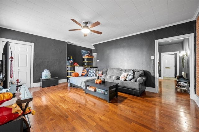 living room with hardwood / wood-style flooring, ceiling fan, and crown molding