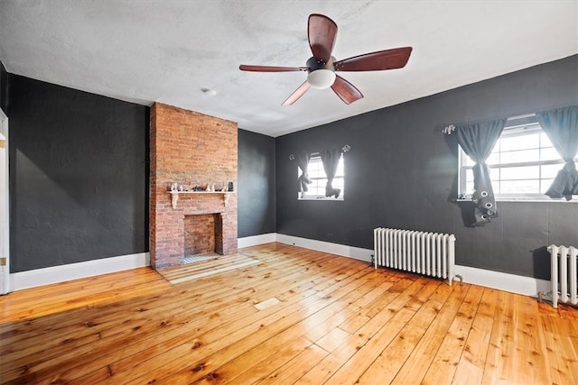 unfurnished living room featuring radiator heating unit, a healthy amount of sunlight, and light hardwood / wood-style flooring