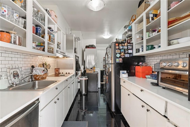 kitchen with dark tile patterned flooring, sink, decorative backsplash, appliances with stainless steel finishes, and white cabinetry