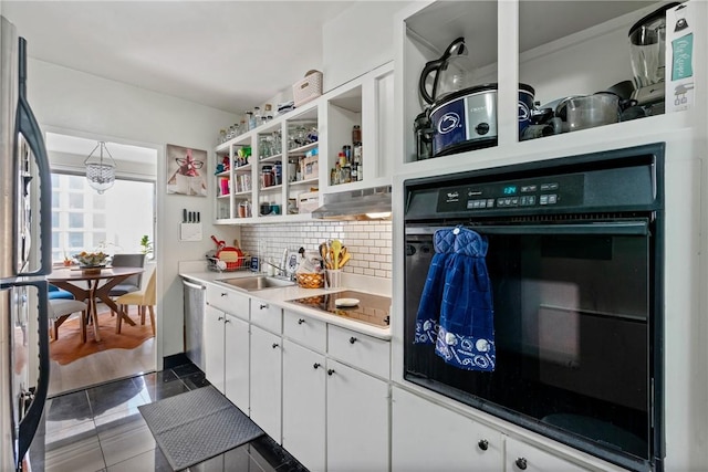 kitchen featuring white cabinets, tasteful backsplash, oven, and stainless steel refrigerator