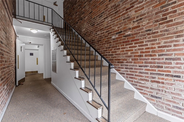 stairs featuring a towering ceiling and brick wall