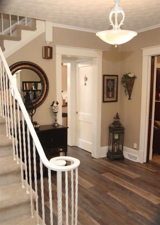 stairs with wood-type flooring and ornamental molding