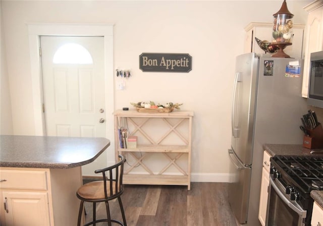 kitchen featuring stainless steel appliances, a breakfast bar area, hanging light fixtures, and dark hardwood / wood-style floors