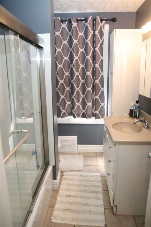 bathroom featuring tile patterned flooring, vanity, and combined bath / shower with glass door