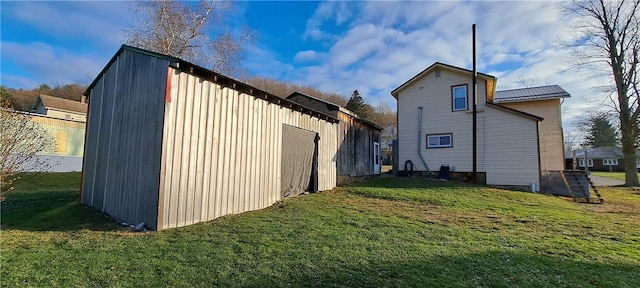 rear view of house featuring an outbuilding and a lawn