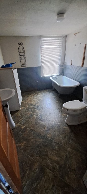 bathroom featuring a bath, a textured ceiling, and toilet