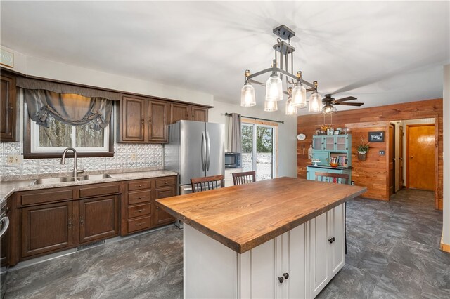 kitchen with butcher block counters, a center island, sink, tasteful backsplash, and stainless steel fridge