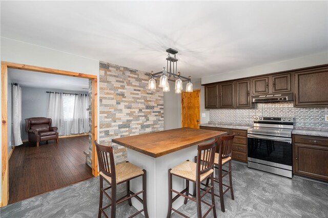 kitchen featuring wood counters, a kitchen breakfast bar, dark hardwood / wood-style flooring, stainless steel range, and dark brown cabinetry