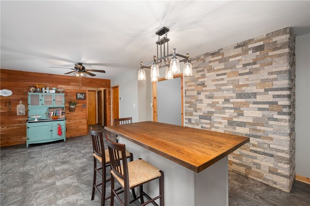 dining area with ceiling fan and wooden walls