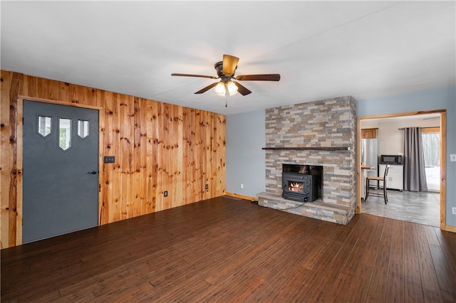 unfurnished living room featuring wood-type flooring, a wealth of natural light, and wooden walls