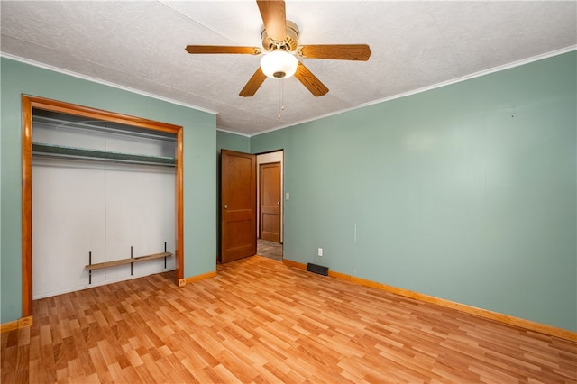 unfurnished bedroom featuring a textured ceiling, ceiling fan, crown molding, light hardwood / wood-style floors, and a closet