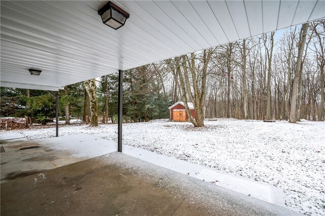 snowy yard featuring a storage unit