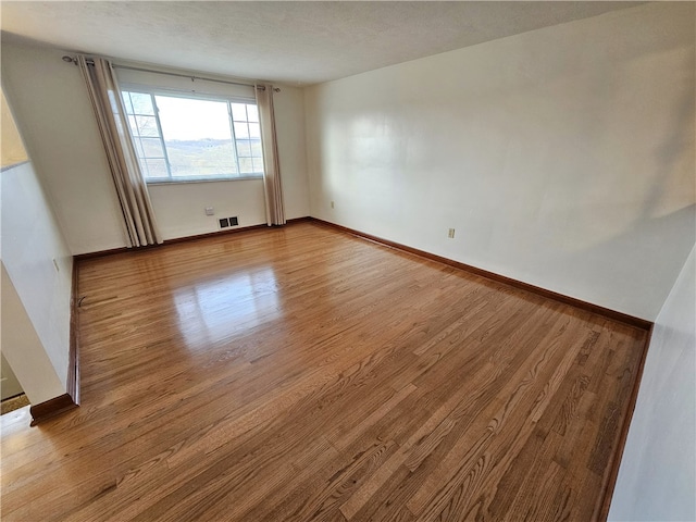 unfurnished room with a textured ceiling and light wood-type flooring