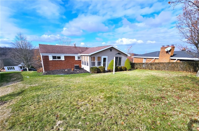 back of house featuring a lawn, a sunroom, and central AC