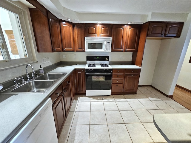 kitchen featuring light tile patterned flooring, white appliances, and sink