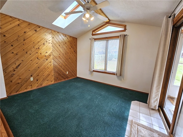 bonus room with light carpet, a textured ceiling, wooden walls, and a healthy amount of sunlight