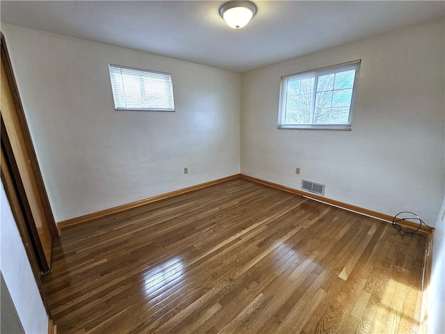 spare room with a wealth of natural light and dark wood-type flooring