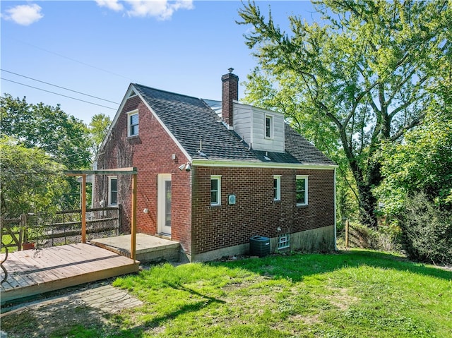 rear view of property with a deck, a yard, and central AC